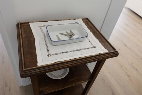 Comodino in legno con panno ricamato bianco e piatto in ceramica per le chiavi presso l'appartamento Solumnia Urban Nest a Milano