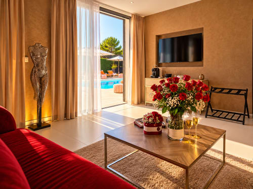 Suite luxueuse à La Villa Monarque, Cap d'Agde avec vue piscine, canapé rouge, dorures et fleurs fraîches