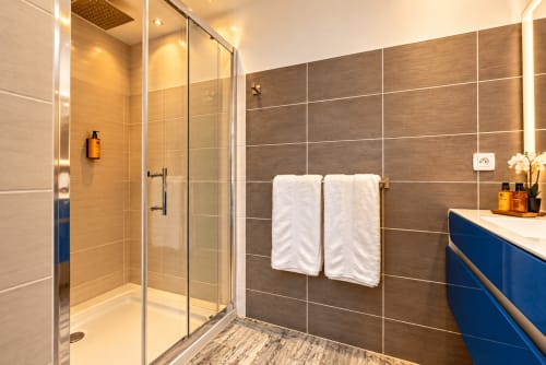 Salle de bain moderne à La Villa Monarque avec douche vitrée, double vasque et porte-serviettes à Cap d'Agde