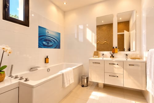 Salle de bain moderne à LA VILLA MONARQUE Cap d'Agde avec double vasque, baignoire îlot et décoration goutte d'eau