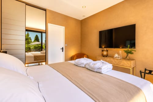 Chambre spacieuse à La Villa Monarque, Cap d'Agde avec lits jumeaux, TV écran plat, penderie miroir et vue sur le jardin