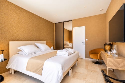 Chambre moderne à La Villa Monarque avec lit queen, papier peint doré chaleureux, armoire miroir et TV écran plat à Cap