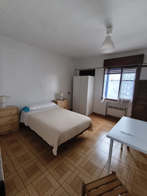 Habitación individual en Pensión Los Pinos Gijón con cama, escritorio de madera, armario y ventana con vistas a la ciudad