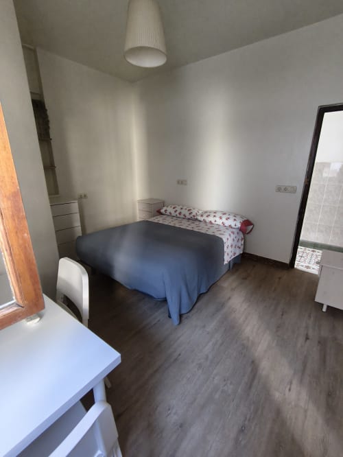 Habitación doble estándar en Pensión Los Pinos Gijón con ropa de cama azul, paredes blancas, suelo de madera e iluminación moderna en techo
