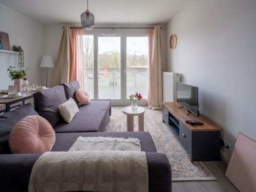 Salon moderne à Le Paradis Des Logis, Pierrefitte sur Seine, avec canapé violet, télévision et vue sur balcon