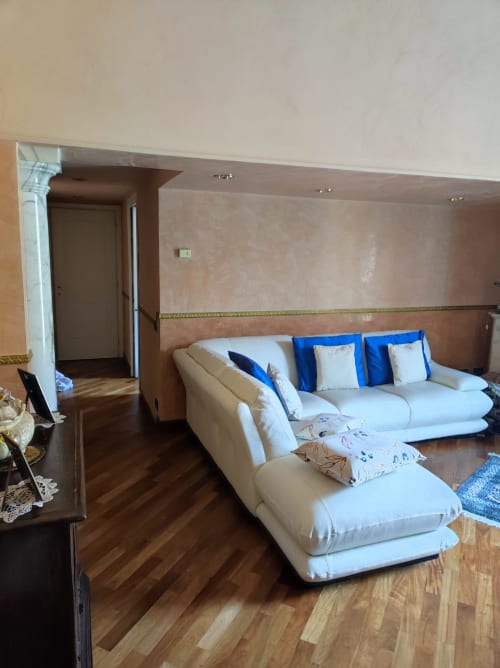 Suite Platone Prestige al GRUPPO PLATONE Alessandria: elegante zona living con divano crema, cuscini blu, pavimenti in legno