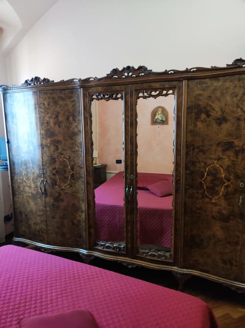 Armadio in legno ornato con specchi e biancheria rosa nella suite Gruppo Platone, Alessandria