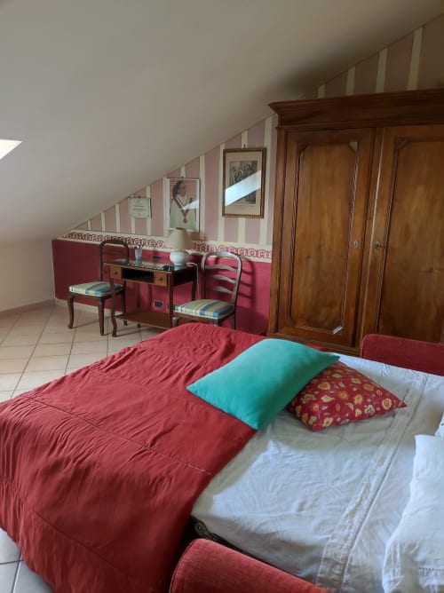 Camera da letto in soffitta a Gruppo Platone Alessandria con biancheria rossa, armadio in legno, pareti a righe