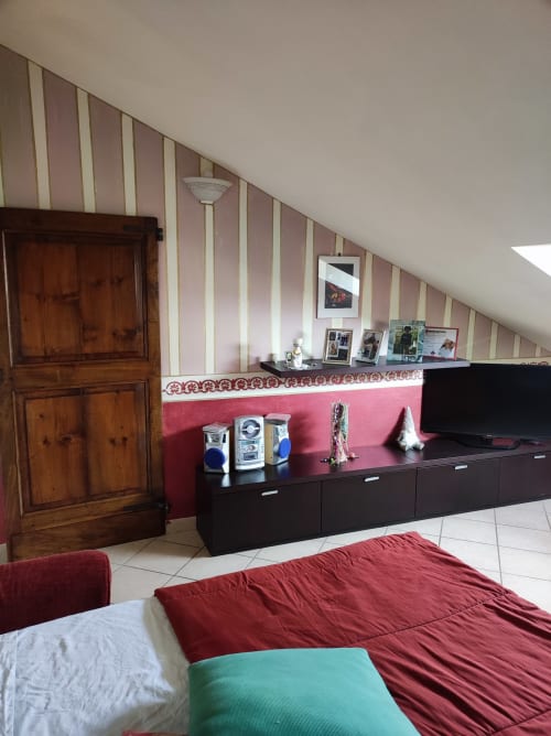 Camera da letto ad Alessandria con pareti a righe rosse, mobile TV nero, porta in legno e arredi moderni presso Gruppo Platone