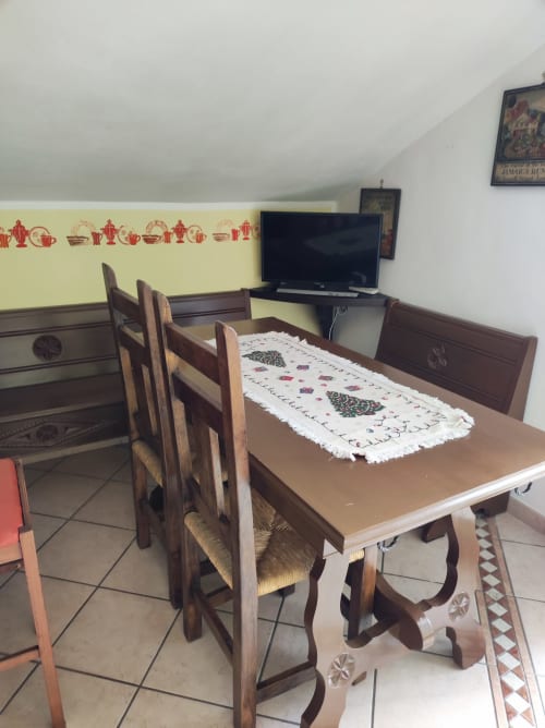 Sala da pranzo dell'appartamento Maison Platone Prestige al Gruppo Platone di Alessandria con tavolo in legno, sedie e TV
