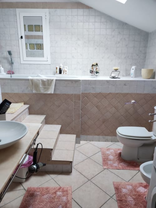 Bagno spazioso presso Gruppo Platone Alessandria con piastrelle in marmo, vasca, wc e lavabo nella maison platone prestige