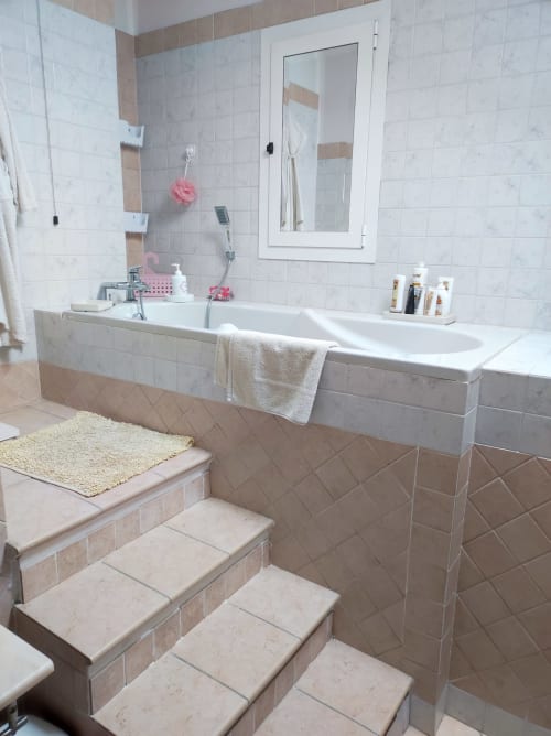 Lussuoso bagno nell'appartamento Gruppo Platone di Alessandria con doppio lavabo, marmo bianco e gradini piastrellati verso la vasca