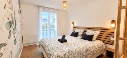 Chambre moderne à l'hôtel NN Patrimoine à Douvaine avec lit en bois, literie motifs, vue sur balcon et ambiance