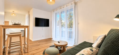 Salon moderne au Frontalier, hôtel NN Patrimoine, Douvaine, avec canapé vert, télévision écran plat et meubles en bois
