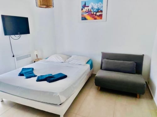 Chambre moderne à la Villa Benedettu aux Villas d'A Storia, Porto-Vecchio, avec lit blanc, canapé gris et télévision écran plat