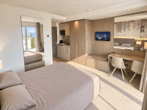 Modern studio at Attica Résidences with lake view, featuring bed, kitchenette, desk, and flat-screen TV