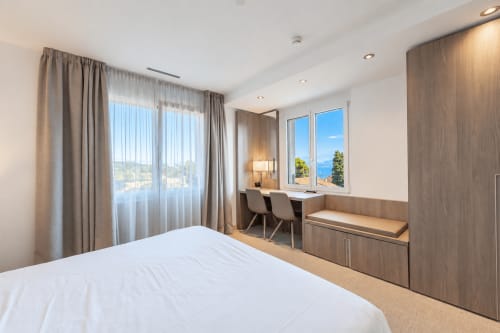 Modern studio bedroom at Attica Résidences in St-Sulpice with lake view, desk, and wood furnishings