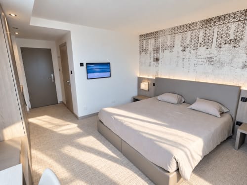 Modern studio bedroom at Attica Résidences in St-Sulpice with bed, flat-screen TV, and minimalist decor