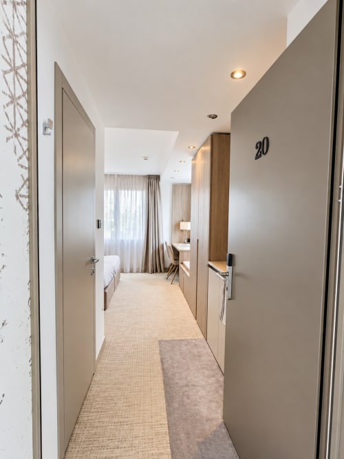 Modern hotel corridor at Attica Résidences in St-Sulpice with room 20 entrance, neutral décor, and ambient lighting