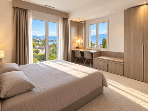 Luxury hotel room at Attica Résidences in St-Sulpice with lake and mountain views, modern furnishings, and natural light