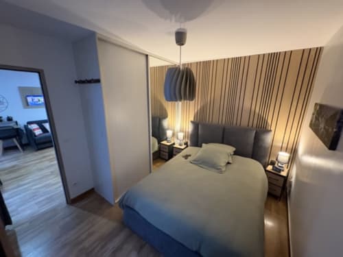 Moderna spavaća soba u Annecy BnB s bračnim krevetom, visilnim rasvjetom, prugastim zlatnim zavjesama i privatnom kupaonicom