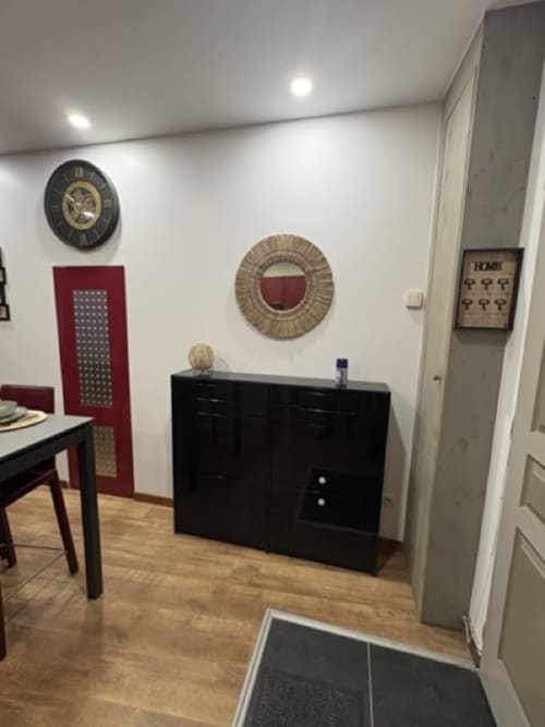Moderna blagovaonica u apartmanu u Annecy-ju s crnim namještajem, zidnim satom i dekorativnim ogledalom