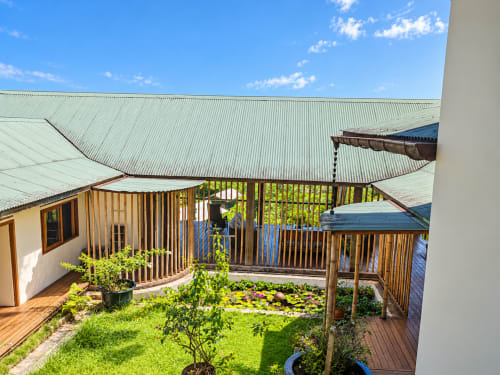 Cour de la maison d'hôtes Fare Tihi Moana à Tumaraa avec terrasse en bois, plantes tropicales et vue sur mer en Polynésie française