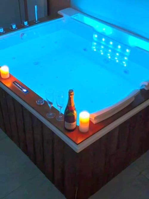 Jacuzzi de luxe aux lumières bleues scintillantes et champagne dans le loft de Gîtes Saint Valéry En Caux