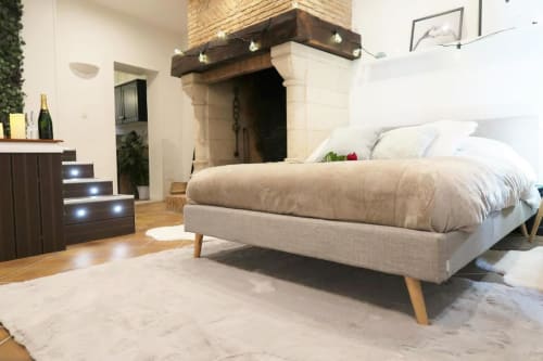 Chambre spacieuse aux Gîtes Saint Valery En Caux avec lit beige, cheminée et mobilier en bois