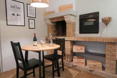 Élégante salle à manger de l'appartement La Suite aux Gîtes Saint Valéry En Caux avec cheminée, bouteilles de vin et meubles en bois