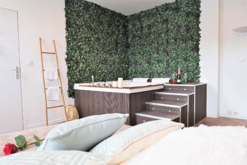 Salle de bain moderne avec baignoire jacuzzi, meuble-lavabo en bois, mur végétal vert et rangements en escalier