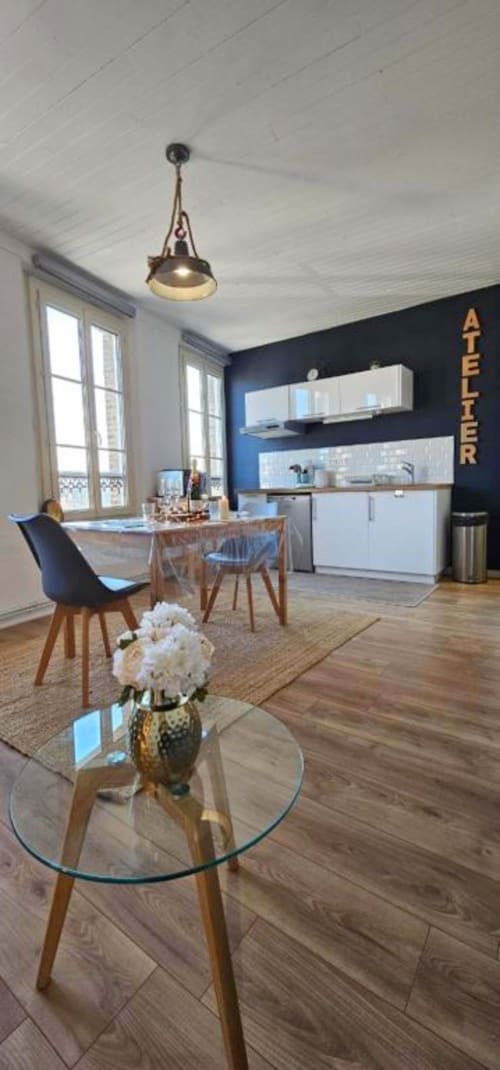 Modern open-plan kitchen and dining area in L'Atelier duplex apartment with sea views, featuring blue accent wall, white