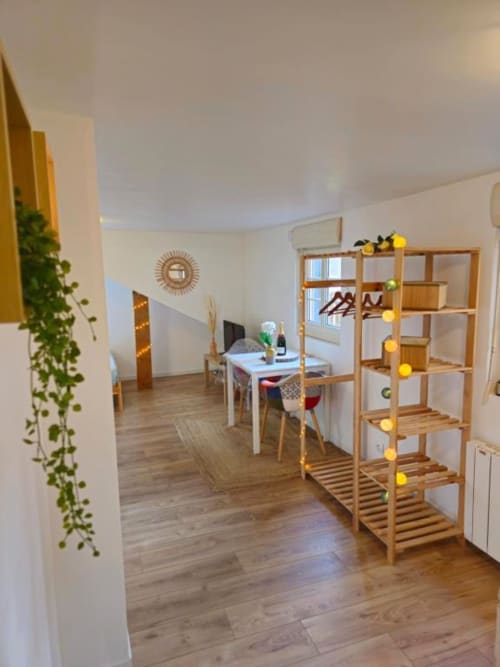 Modern studio apartment with wooden shelving, work desk, plants, and warm lighting in Saint-Valery-en-Caux gite