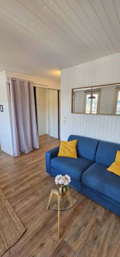 Modern living room with blue sofa, yellow pillows, and floral arrangement at L'Atelier duplex in Saint Valery En Caux