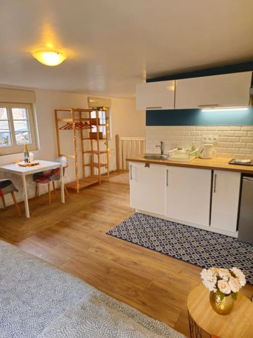 Modern kitchen and dining area in Sous les Toits apartment at Gites Saint Valery En Caux, featuring white cabinetry, wooden