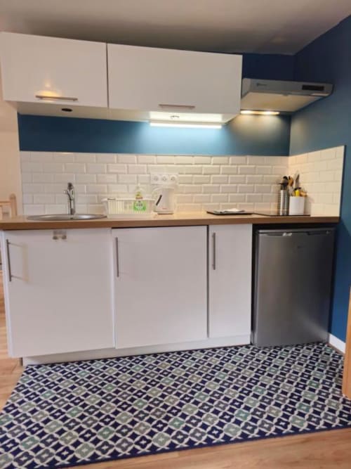 Modern kitchen in Gites Saint Valery En Caux apartment with white cabinets, subway tile backsplash, and patterned floor
