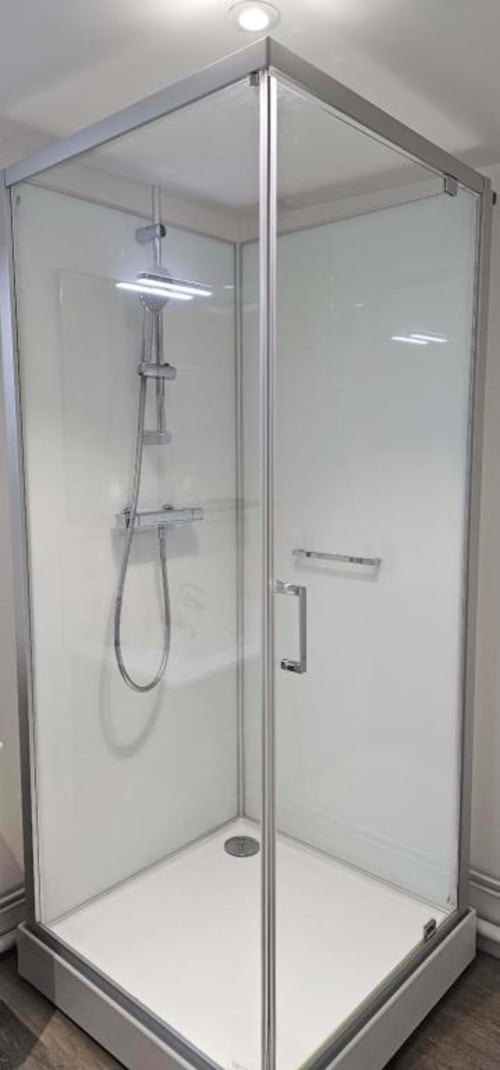 Modern glass shower enclosure with rainfall showerhead and handheld sprayer at Gites Saint Valery En Caux apartment bathroom.