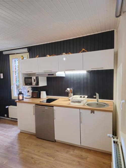 Cuisine moderne de l'appartement L'or Noir aux Gîtes Saint Valéry En Caux avec armoires blanches, plan de travail bois et noir