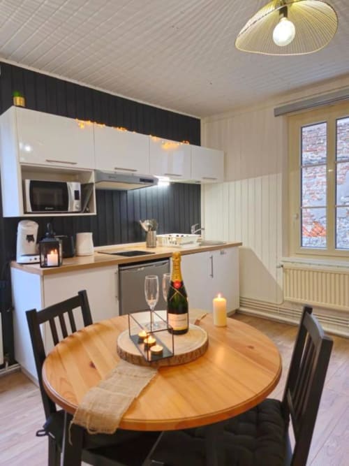 Cuisine et salle à manger modernes aux Gîtes Saint Valery En Caux avec table ronde en bois, armoires blanches