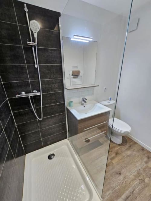 Salle de bain moderne de l'appartement L'or Noir aux Gîtes Saint Valéry en Caux avec douche ouverte, vasque et toilettes