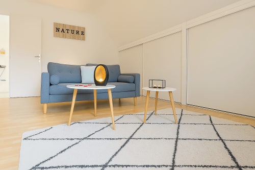 Modern living room in Nid douillet apartment at Gites Saint Valery En Caux with blue sofa, geometric patterned rug, and city
