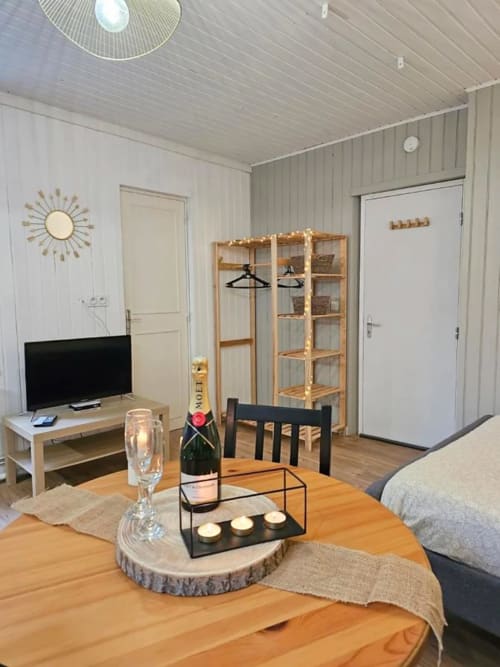 Studio moderne à Saint-Valery-en-Caux : parquet, kitchenette, TV, coin repas et étagères décoratives.