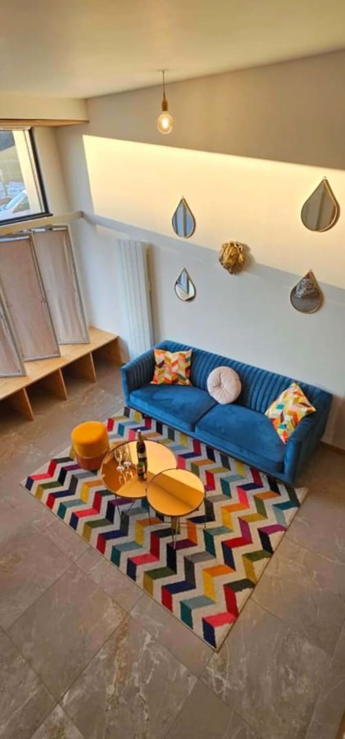Salon moderne aux Gîtes Saint Valery En Caux avec canapé bleu, tapis coloré et accents muraux décor