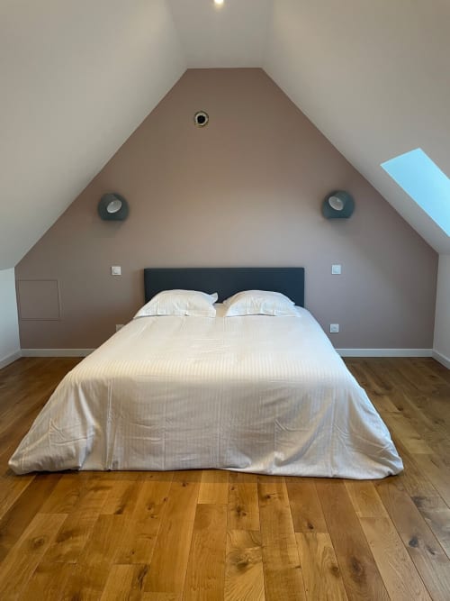 Chambre mansardée du cottage Molinet avec literie blanche, murs taupe et parquet