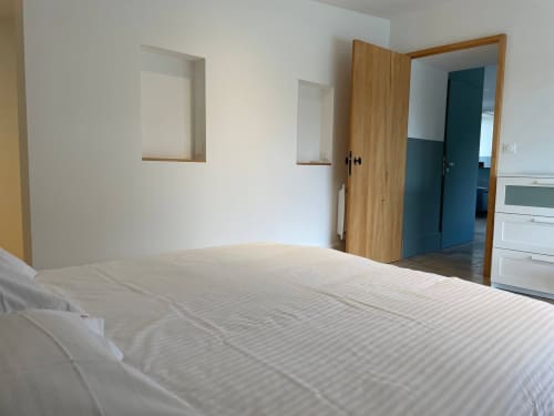 Chambre moderne du gîte Molinet avec literie blanche, portes en bois et décoration minimaliste