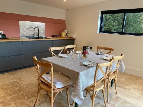 Salle à manger et cuisine du gîte à Molinet avec chaises en bois, table dressée et appareils modernes
