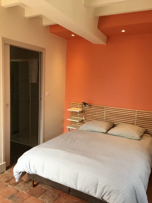 Chambre de cottage moderne à Molinet avec mur d'accent orange, tête de lit en bois et accès à la salle de bain attenante