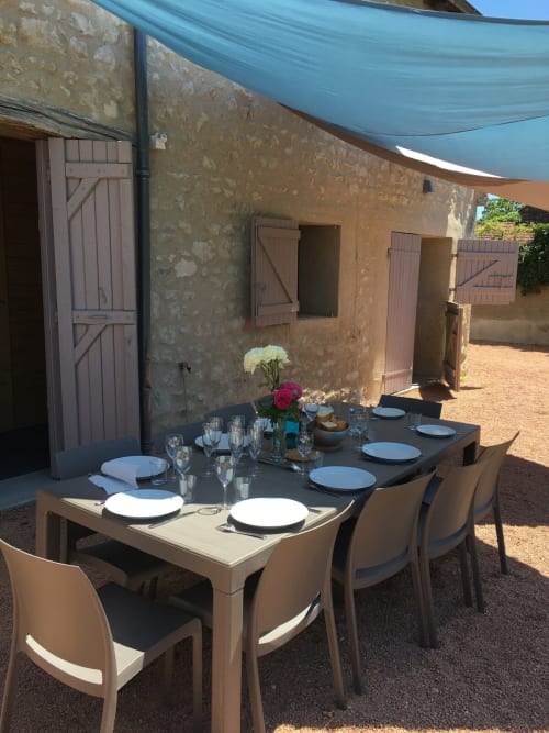 Coin repas extérieur au gîte de LGA à Molinet avec table dressée, auvent bleu et bâtisses en pierre rustique