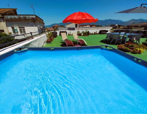 Piscina azzurra brillante presso il Palazzo di Donna a Sant'Egidio del Monte Albino con ombrellone rosso e lettini