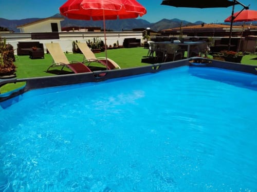 Piscina azzurra luminosa con ombrelloni rossi e lettini presso l'hotel Palazzo di Donna a Sant'Egidio del Monte Albino